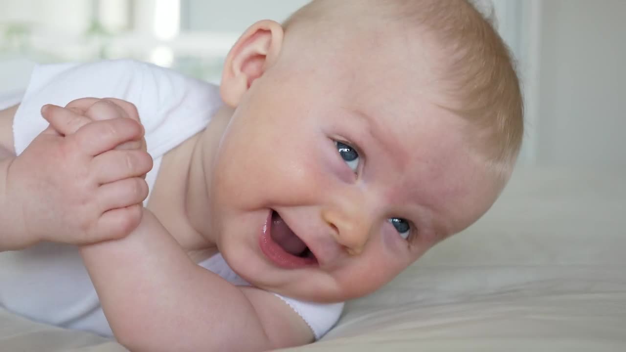 Stock Video Baby Smiles And Rolls Over In White Bedroom Live Wallpaper For PC