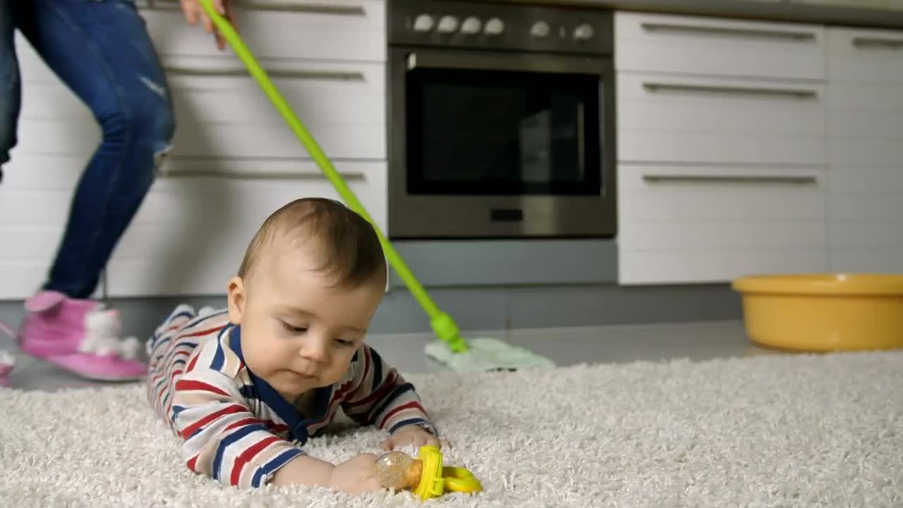 Stock Video Baby Lying On A Rug While Her Mother Cleans Behind Live Wallpaper For PC