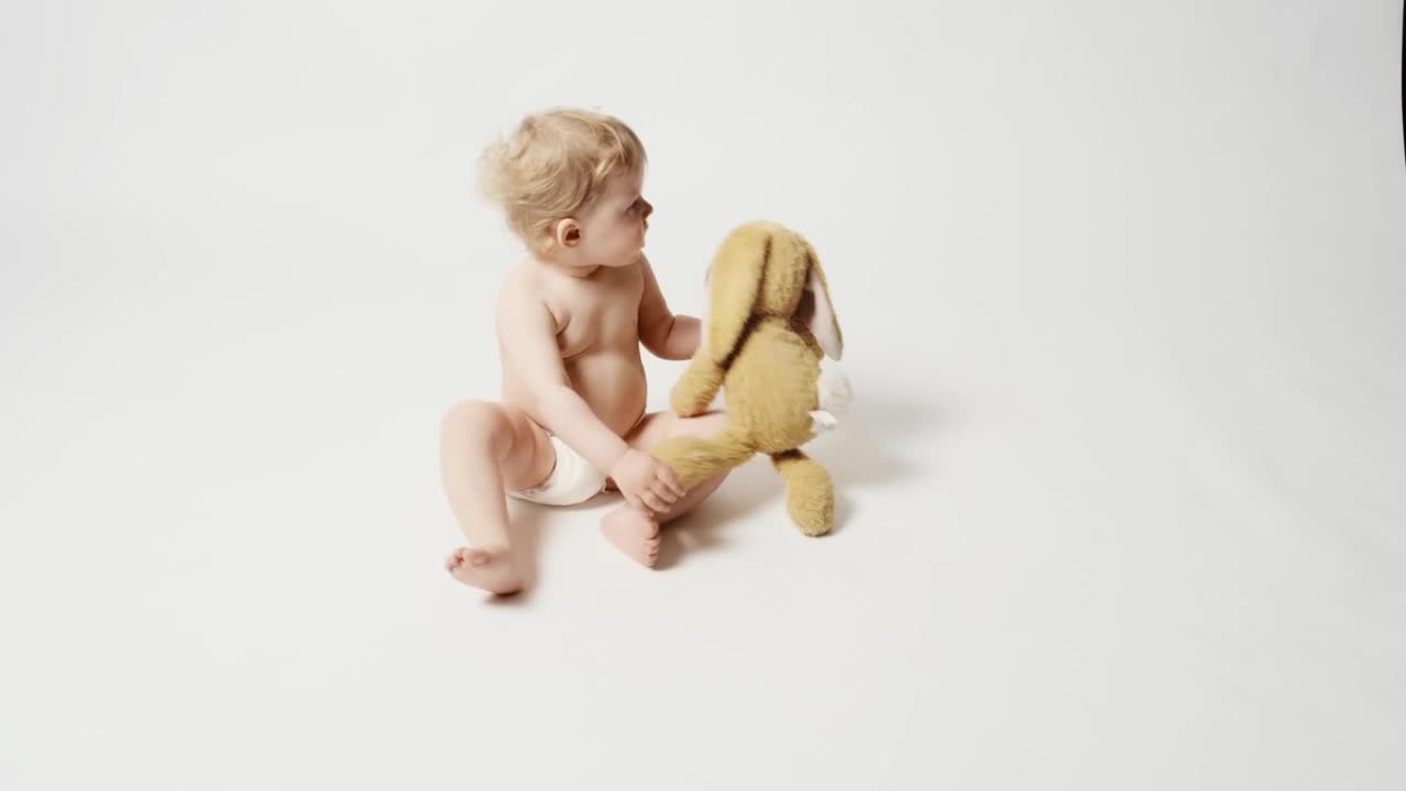 Stock Video Baby Girl With Plushie Sitting On A White Background Live Wallpaper For PC