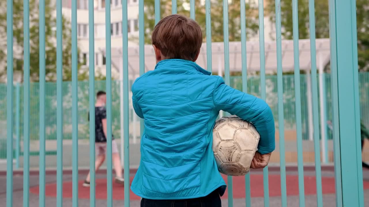 Stock Video Boy Holding Deflated Ball Watching Other Kids Playing Football Live Wallpaper For PC