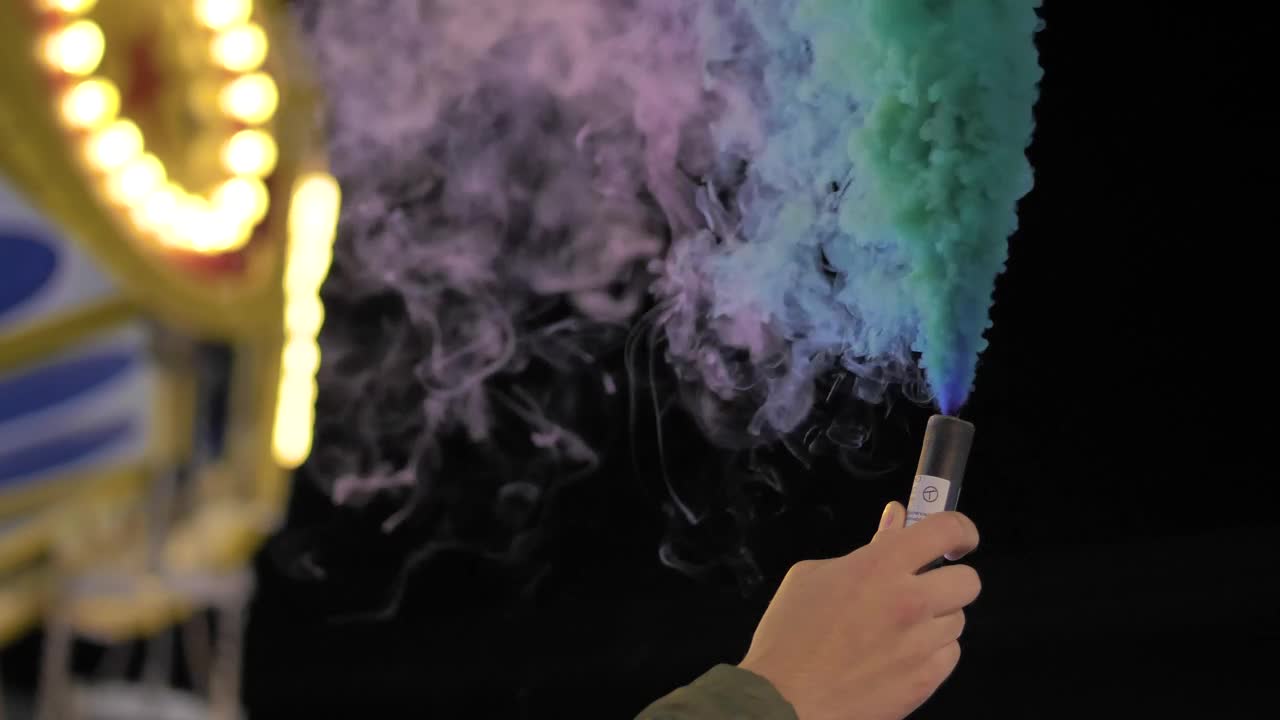 Stock Video Hand Holding A Multicolored Smoke Bomb At The Fair Live Wallpaper For PC