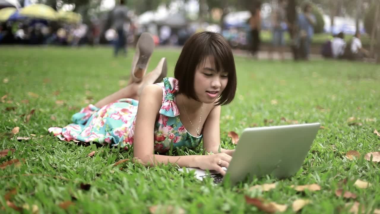 Stock Video Girl Lying In A Park With A Computer Live Wallpaper For PC