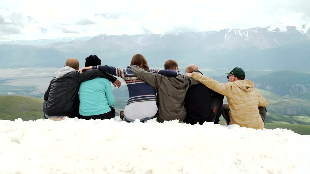 Stock Video Hugging Friends Look At Mountain Landscape From Snowy Ridge Animated Wallpaper