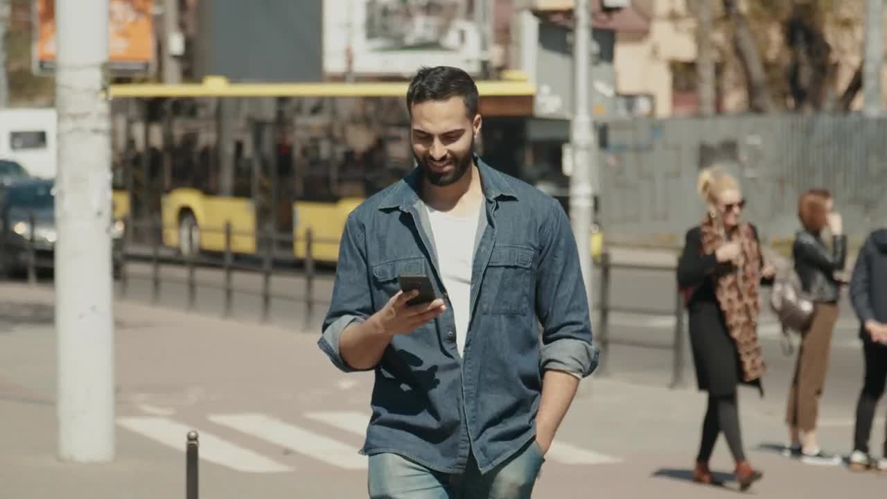 Stock Video Hopeful Man Smiles At Social Media While Walking Through City Animated Wallpaper