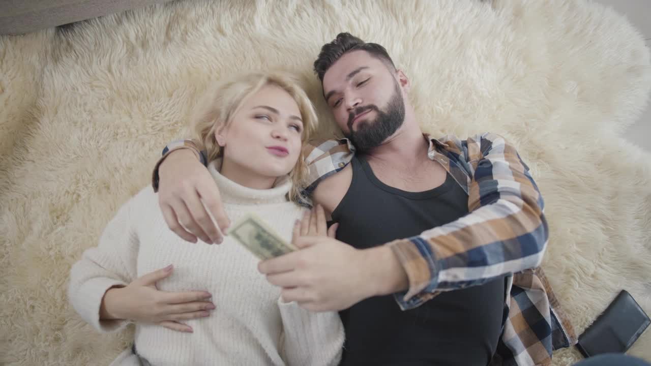 Stock Video Happy Rich Couple Lay On Rug And Count Cash Animated Wallpaper
