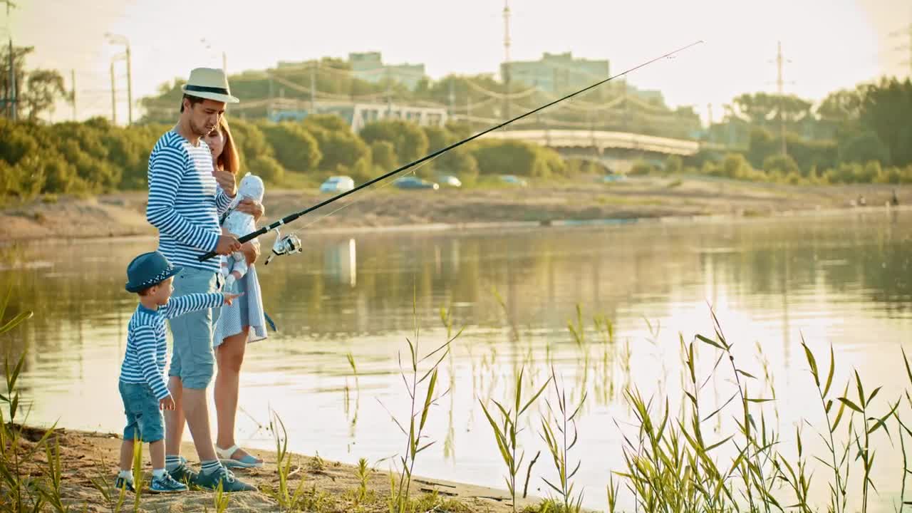 Stock Video Happy Family Fishing On The Shore Of A Lake Animated Wallpaper