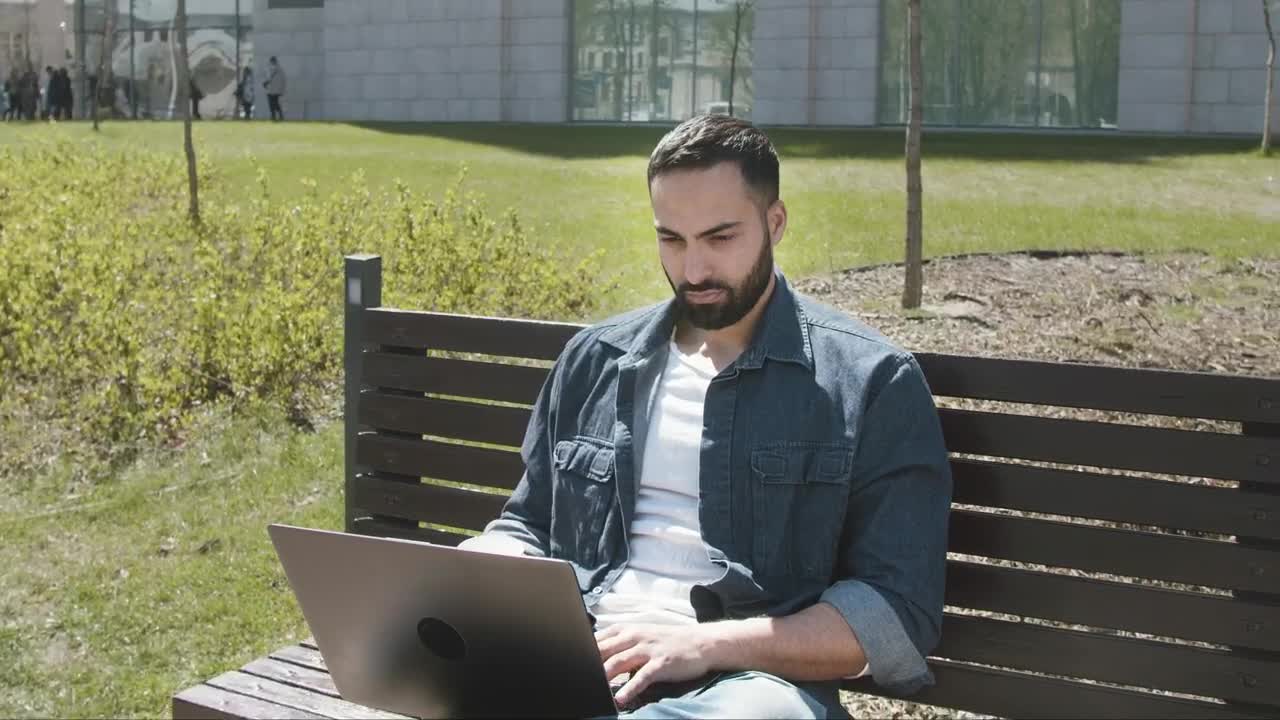 Stock Video Handsome Arab Man Sitting On Park Bench With Laptop Animated Wallpaper