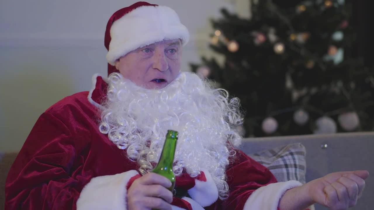 Stock Video Man In Santa Costume Drinks Beer On Sofa Animated Wallpaper
