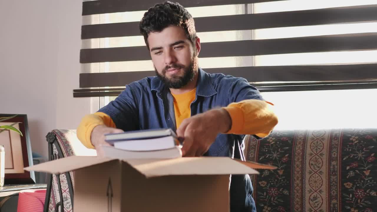 Stock Video Man In His Living Room Finishes Packing A Box To Animated Wallpaper