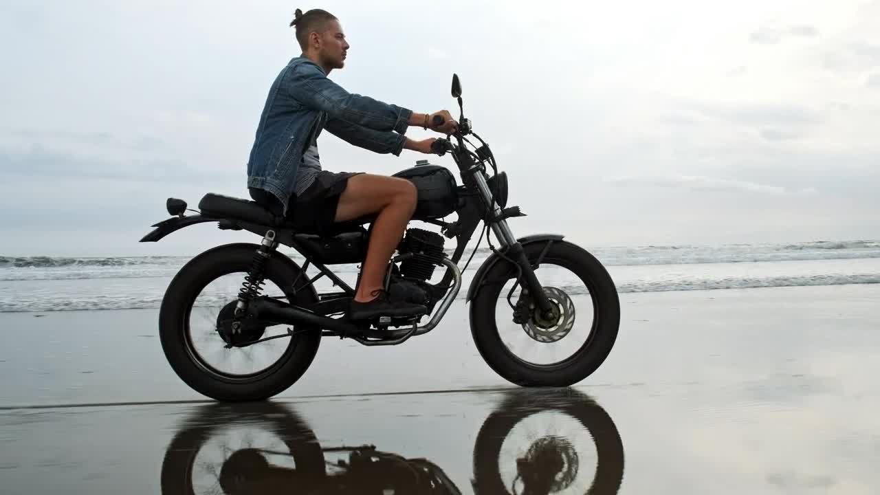 Stock Video Man In Denim Jacket Riding Motorcycle On Beach Animated Wallpaper