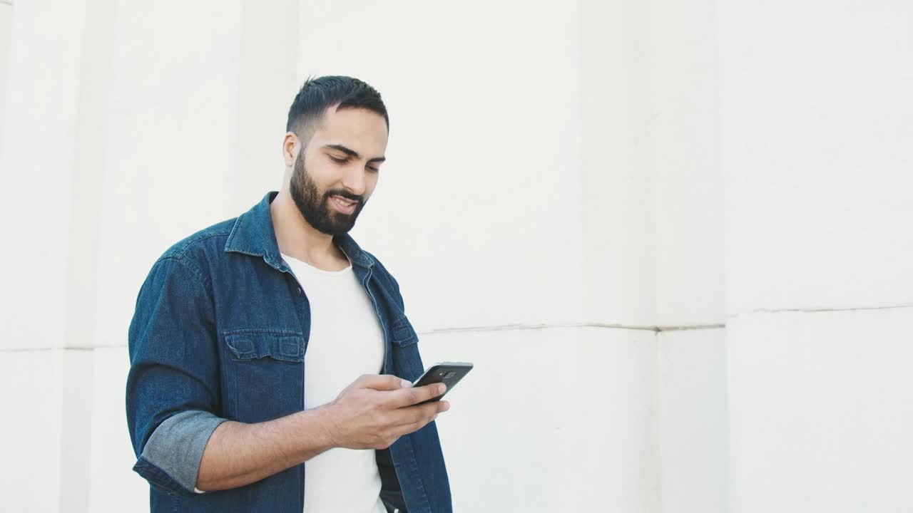 Stock Video Man In Denim Jacket Holding Phone And Walking Along White Animated Wallpaper