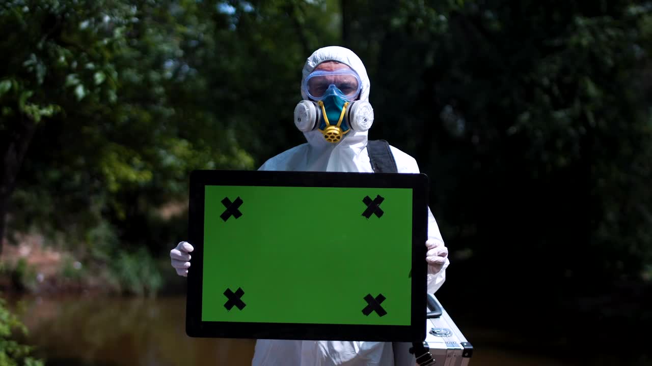Stock Video Man In Biohazard Suit Holding A Greenscreen Sign Animated Wallpaper