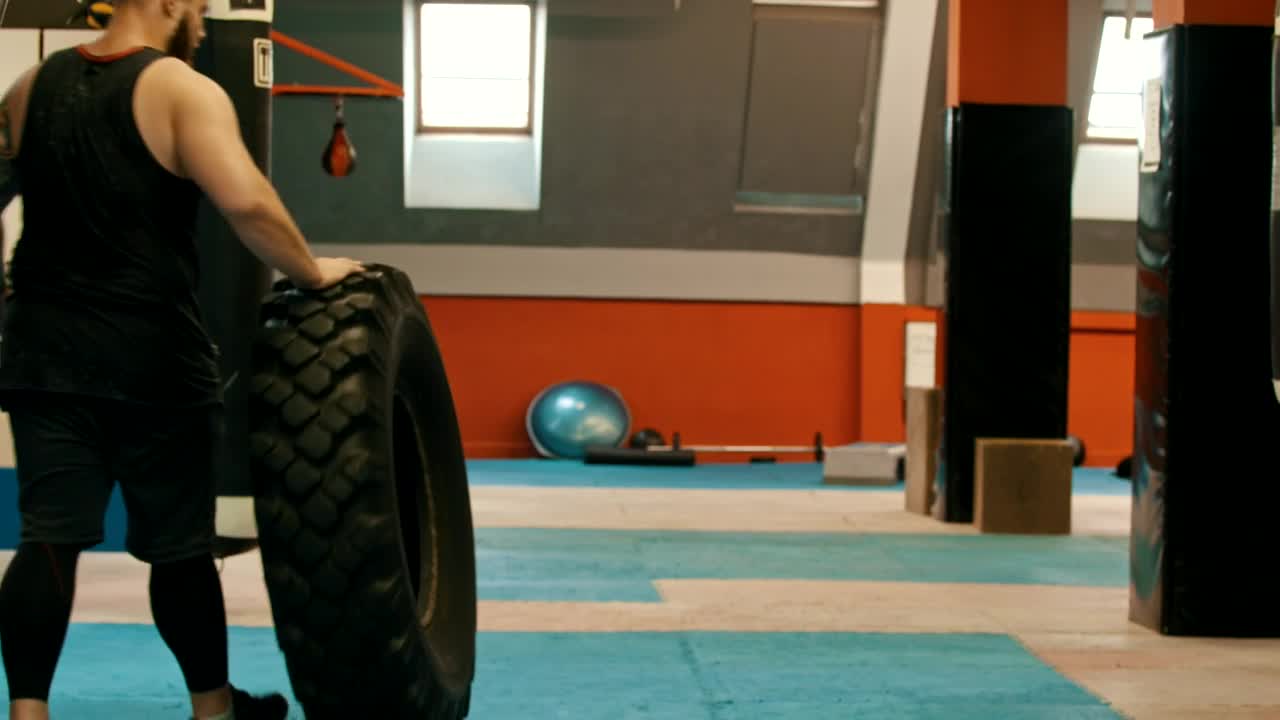 Stock Video Man In A Gym Walking With A Big Truck Wheel Animated Wallpaper