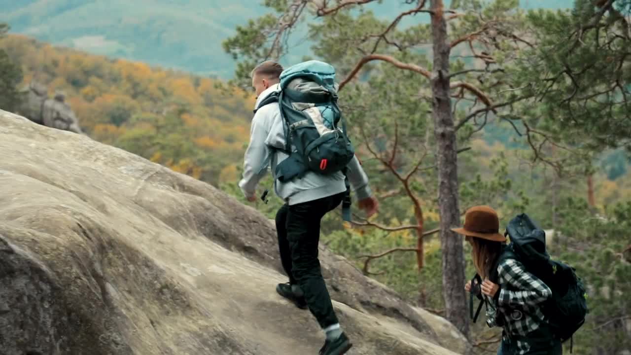 Stock Video Man Helps Girlfriend Climb Up Rock During Hike Animated Wallpaper