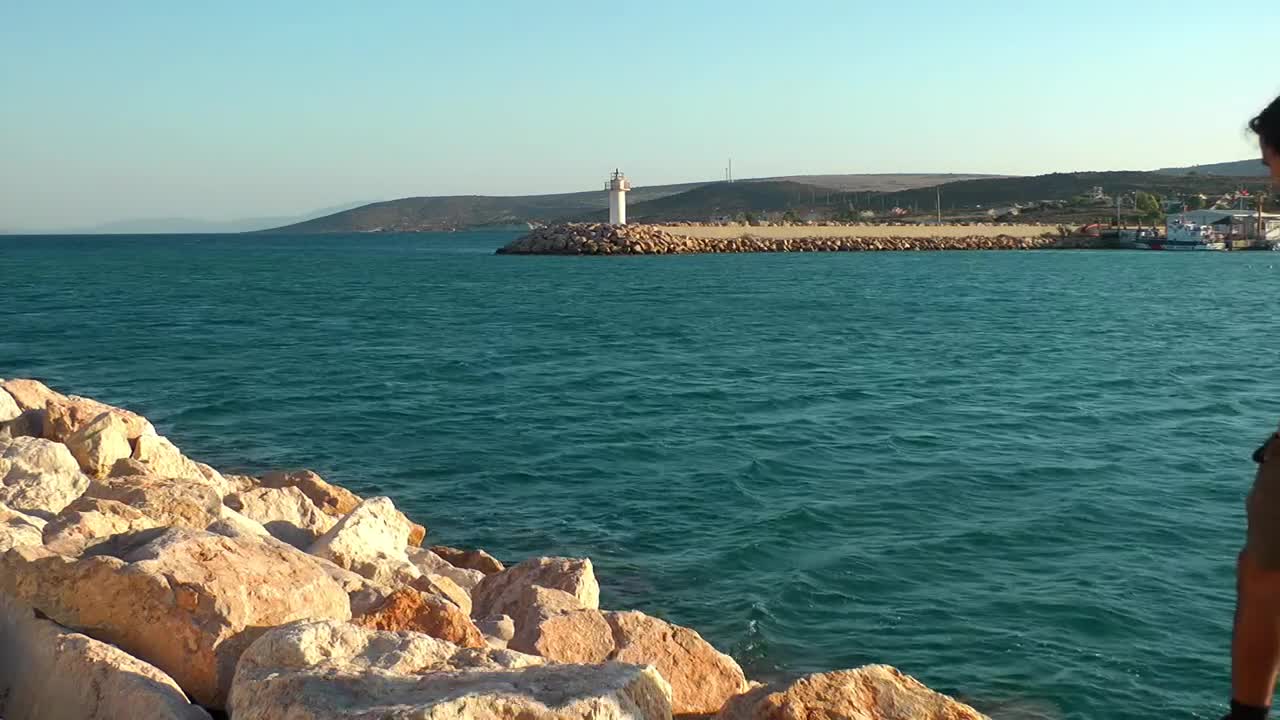 Stock Video Man Exploring A Rocky Hill By The Sea Animated Wallpaper