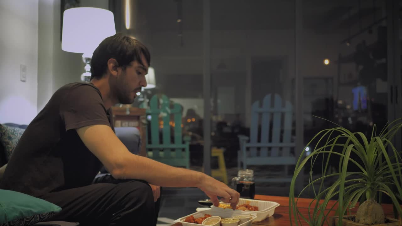 Stock Video Man Eats Watching Television On A Rainy Night Animated Wallpaper