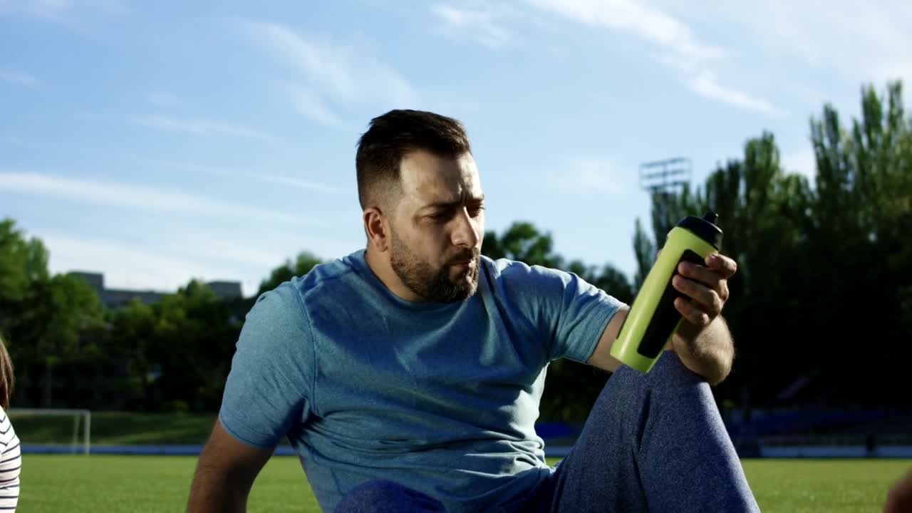 Stock Video Man Drinks Water Sitting On The Park Animated Wallpaper