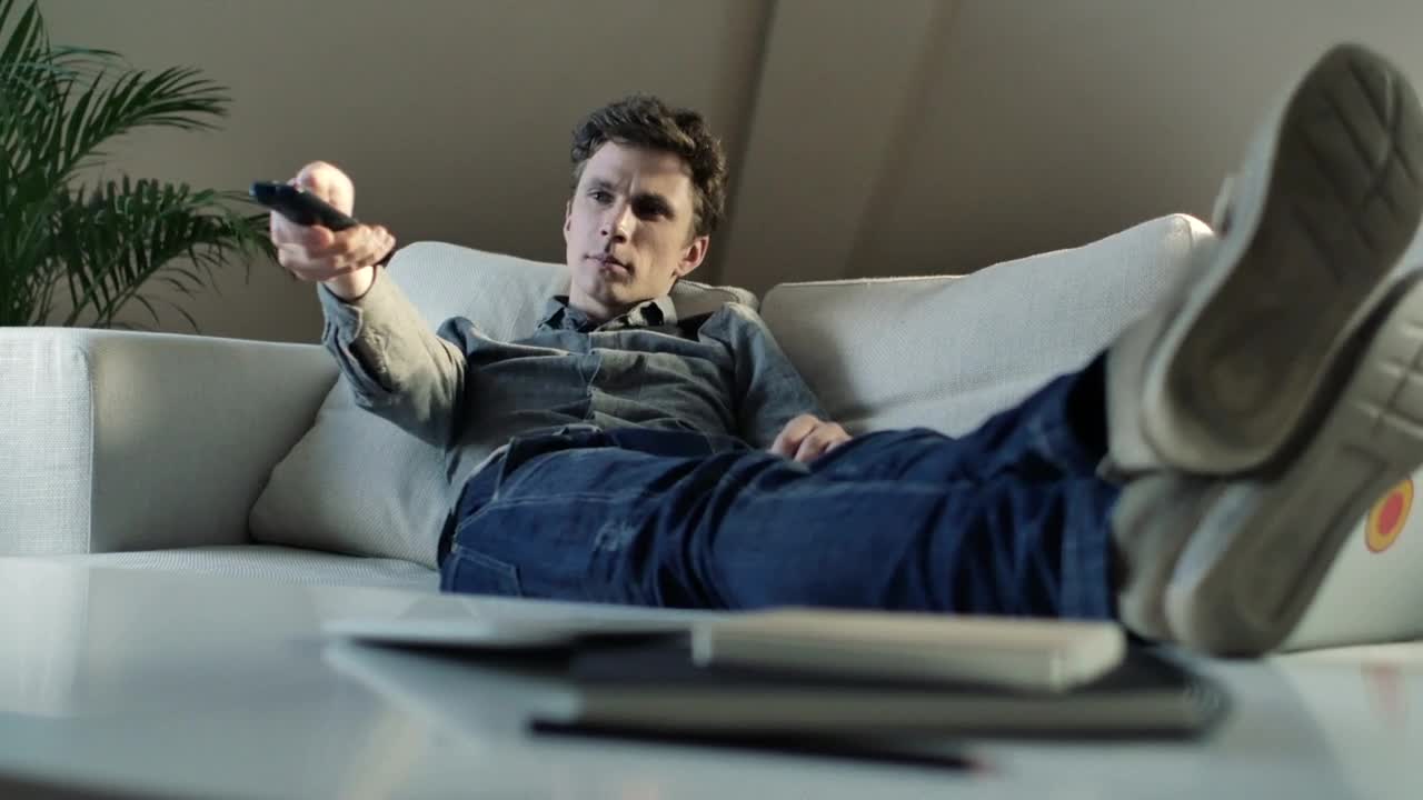 Stock Video Man Changing The Tv Channels From The Couch Animated Wallpaper