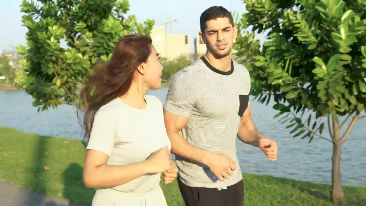 Stock Video Man And Woman Running Through A Sunny Park Animated Wallpaper
