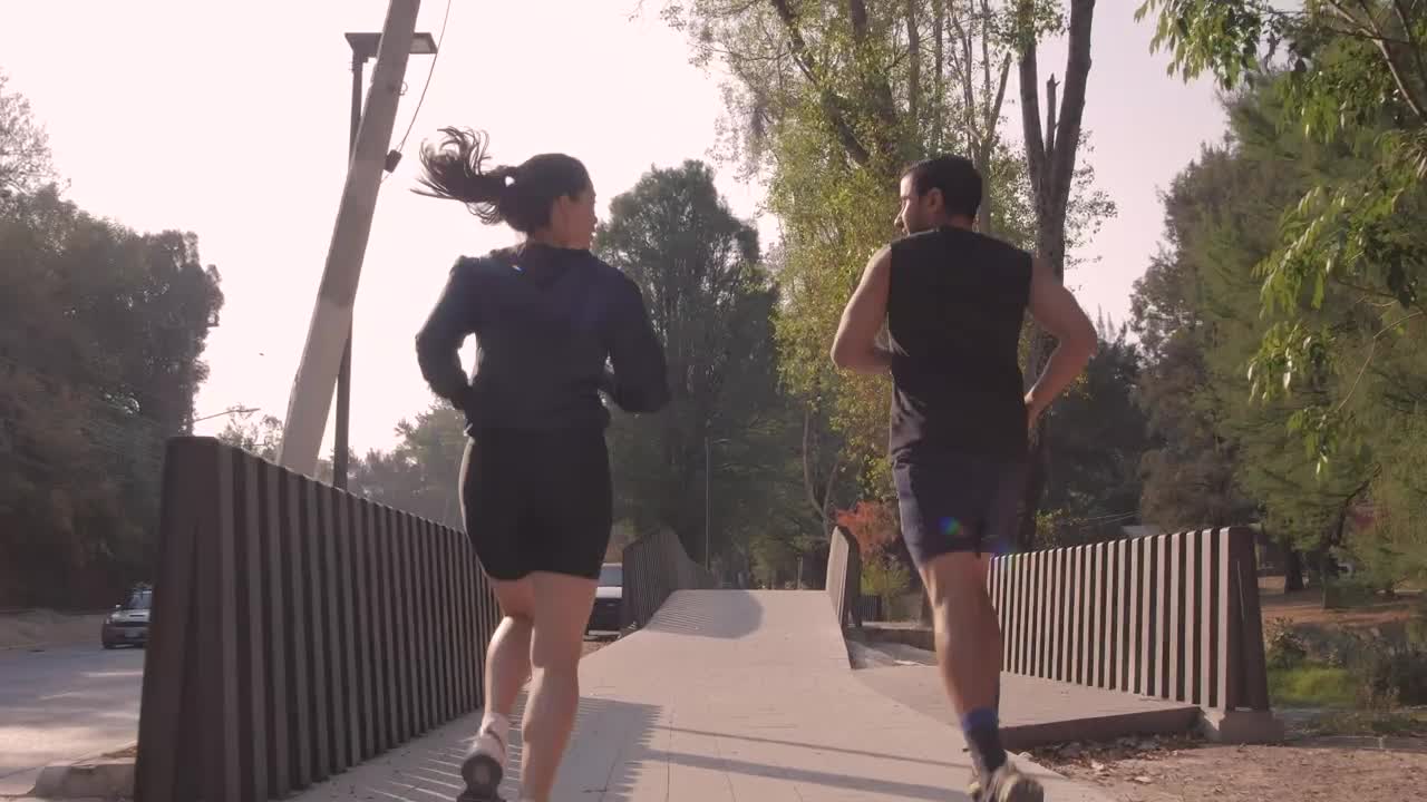 Stock Video Man And Woman Jogging Through A Park In The City Animated Wallpaper