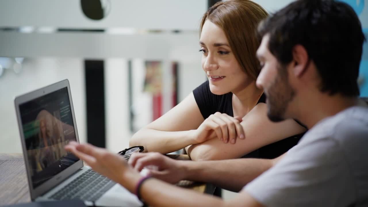 Stock Video Man And Woman Commenting On An Image On A Laptop Animated Wallpaper