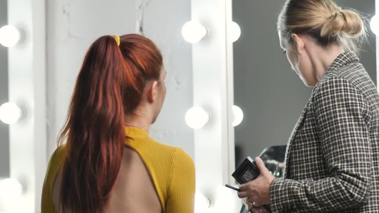 Stock Video Makeup Artist Putting Makeup On A Model In Front Of Animated Wallpaper