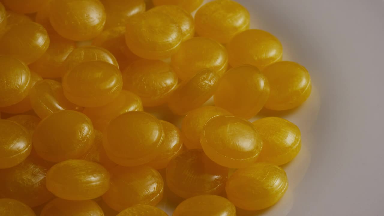 Stock Video Little Yellow Candies Turning Slow On A Plate Animated Wallpaper