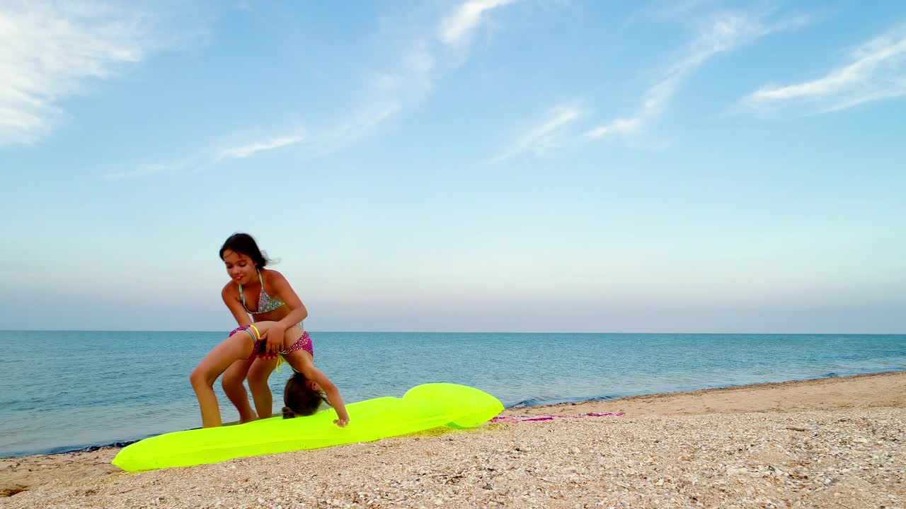 Stock Video Little Sisters Practice Gymnastics On The Seashore Animated Wallpaper