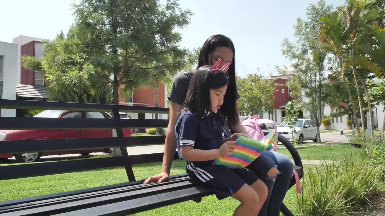 Stock Video Little Girl With Her Mom Reading Together In A Park Animated Wallpaper