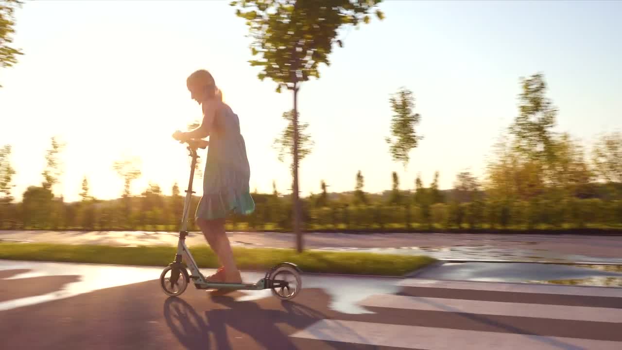 Stock Video Little Girl Riding A Scooter Through The Street Animated Wallpaper