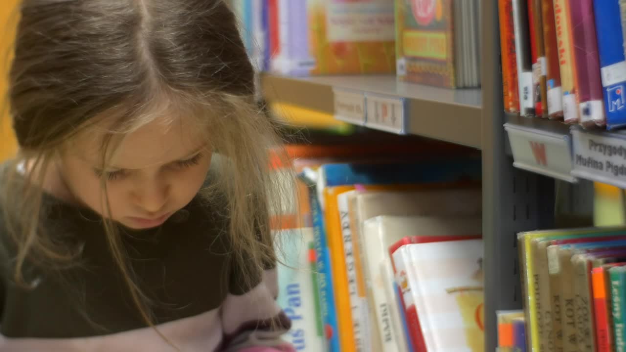 Stock Video Little Girl Reading A Book In A Library Animated Wallpaper