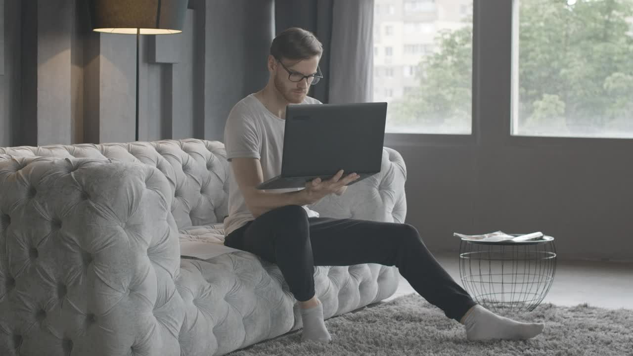 Stock Video Millennial Man Working In Minimalist Living Roo Animated Wallpaper