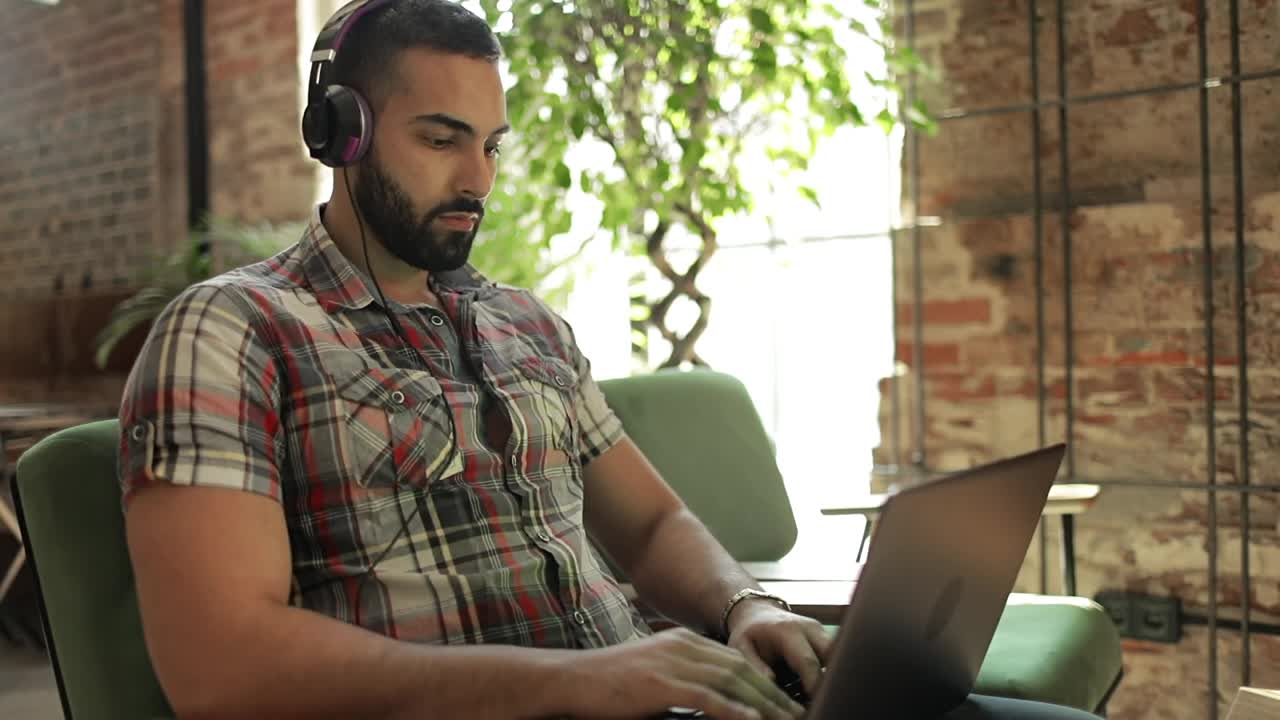 Stock Video Man Works On Laptop With Headphones In Coworking Spac Animated Wallpaper