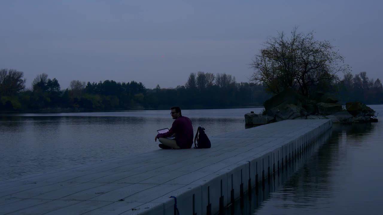 Stock Video Man With A Laptop On The Shore Of A Lak Animated Wallpaper