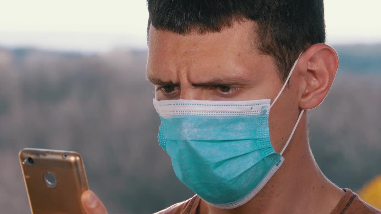 Stock Video Man With A Face Mask Looking At Smart Phon Animated Wallpaper