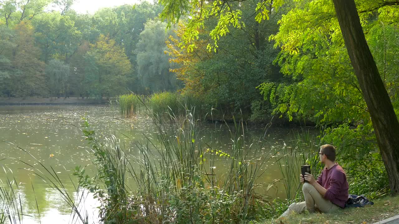 Stock Video Man With A Book Sitting By The Riversid Animated Wallpaper