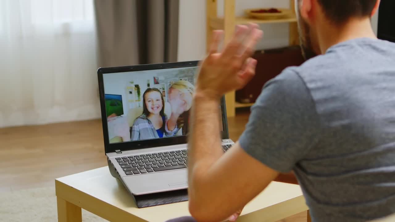 Stock Video Man Waves Hello To Family On Video Cal Animated Wallpaper