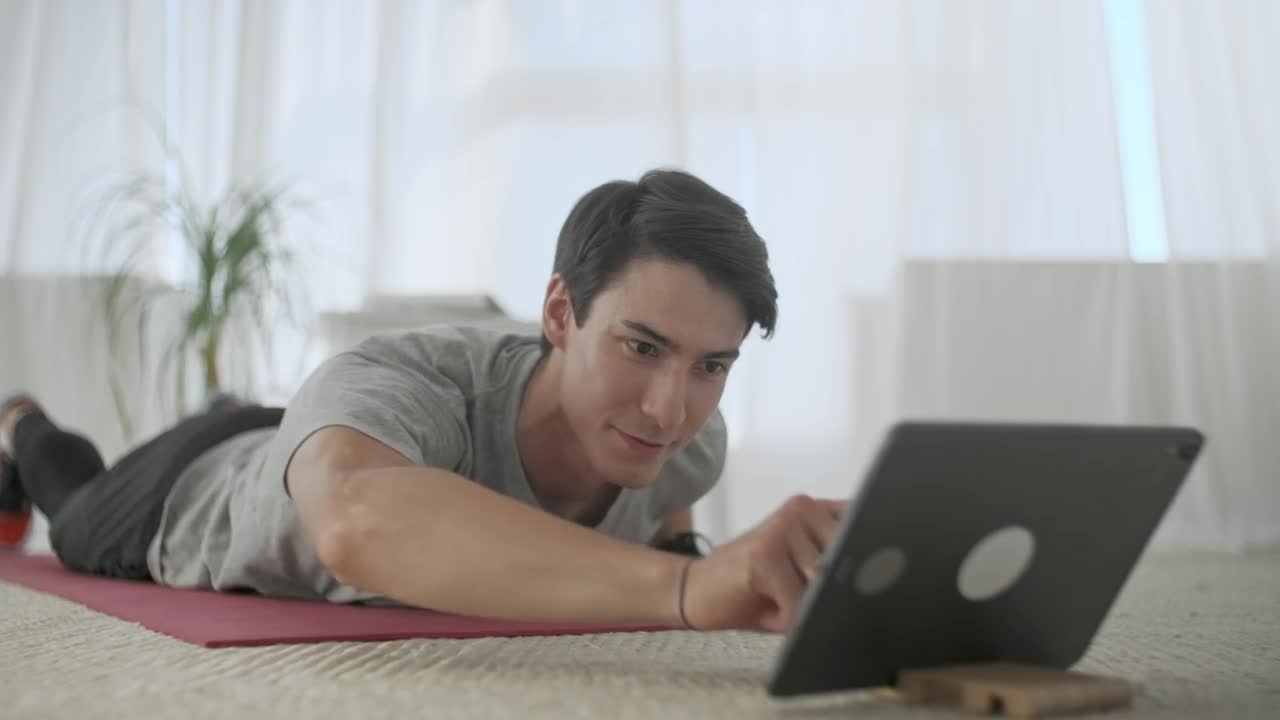Stock Video Man Watching Exercises On A Tablet To Practice The Animated Wallpaper