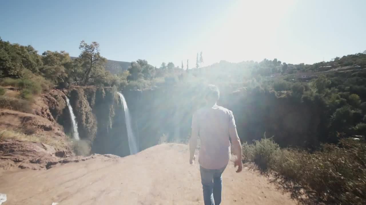 Stock Video Man Walks To A Deep Canyon With Waterfall Animated Wallpaper
