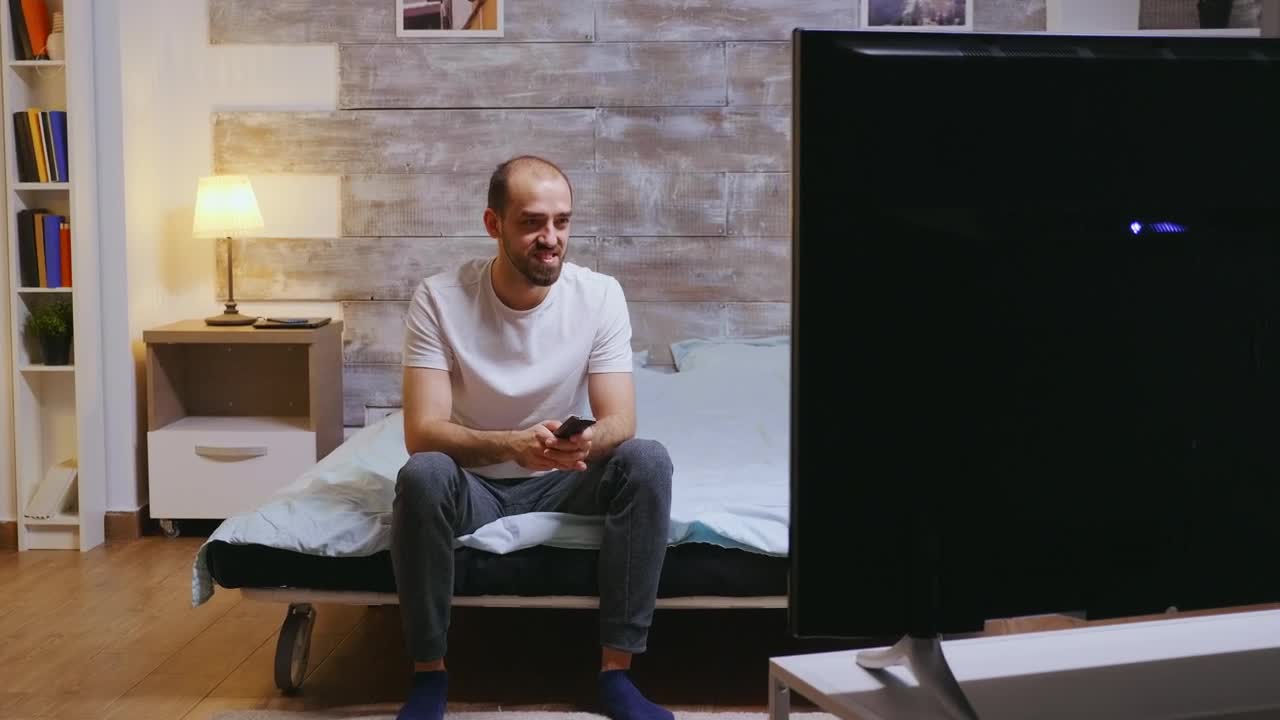 Stock Video Man Sits On Bed Laughing At Comedy On T Animated Wallpaper