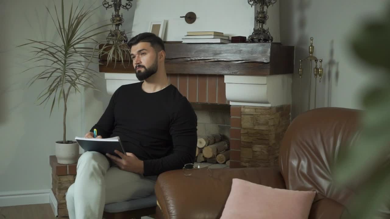 Stock Video Man Sits In Living Room Thinking And Writin Animated Wallpaper