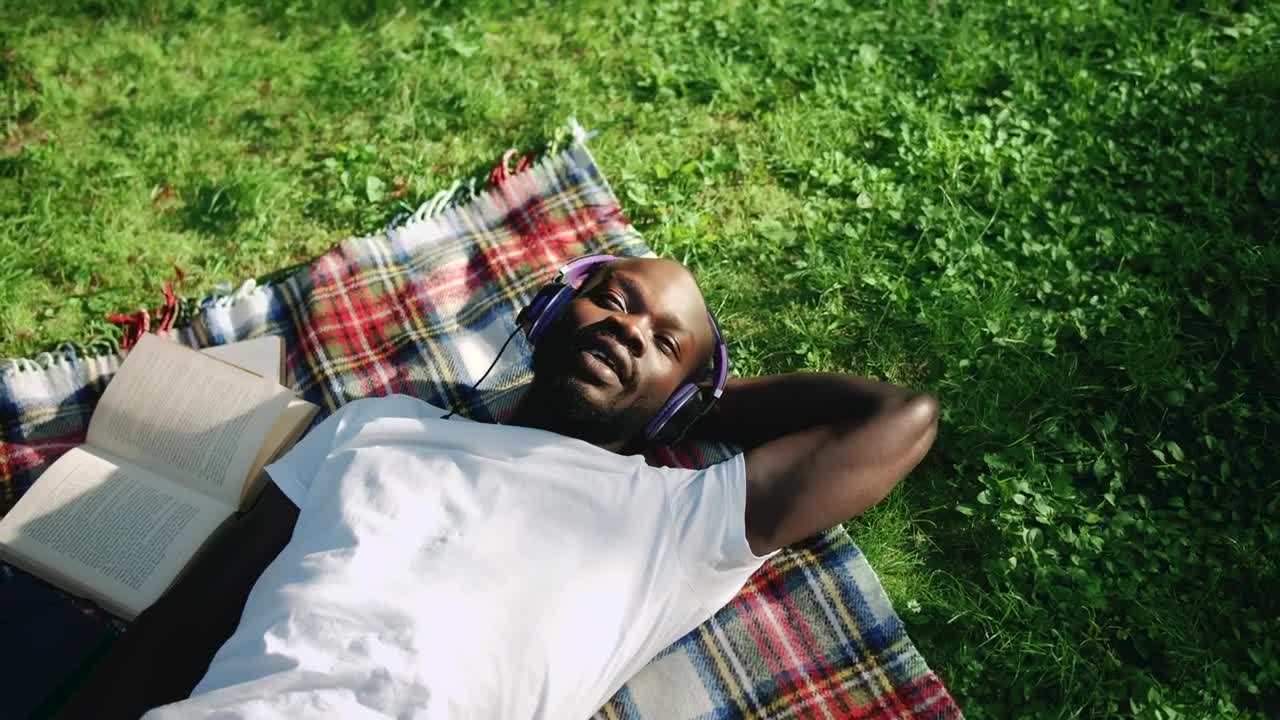 Stock Video Man Sings Along To Music Lying In Park With Headphone Animated Wallpaper