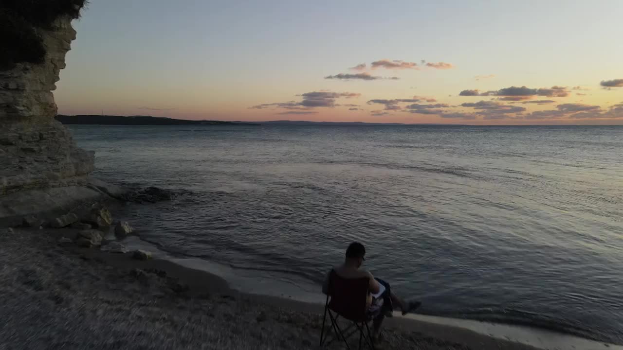 Stock Video Man Reading A Book Near The Seashor Animated Wallpaper