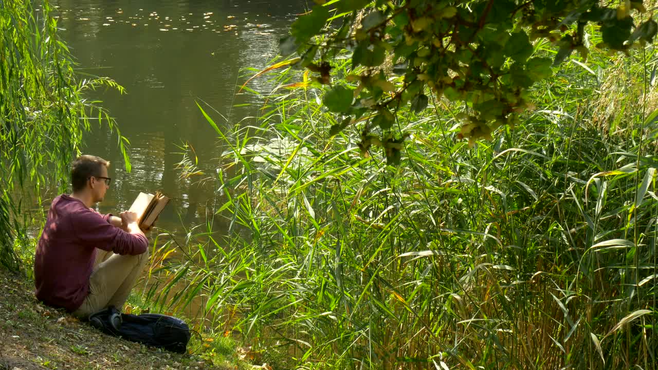 Stock Video Man Reading A Book In The River Shor Animated Wallpaper