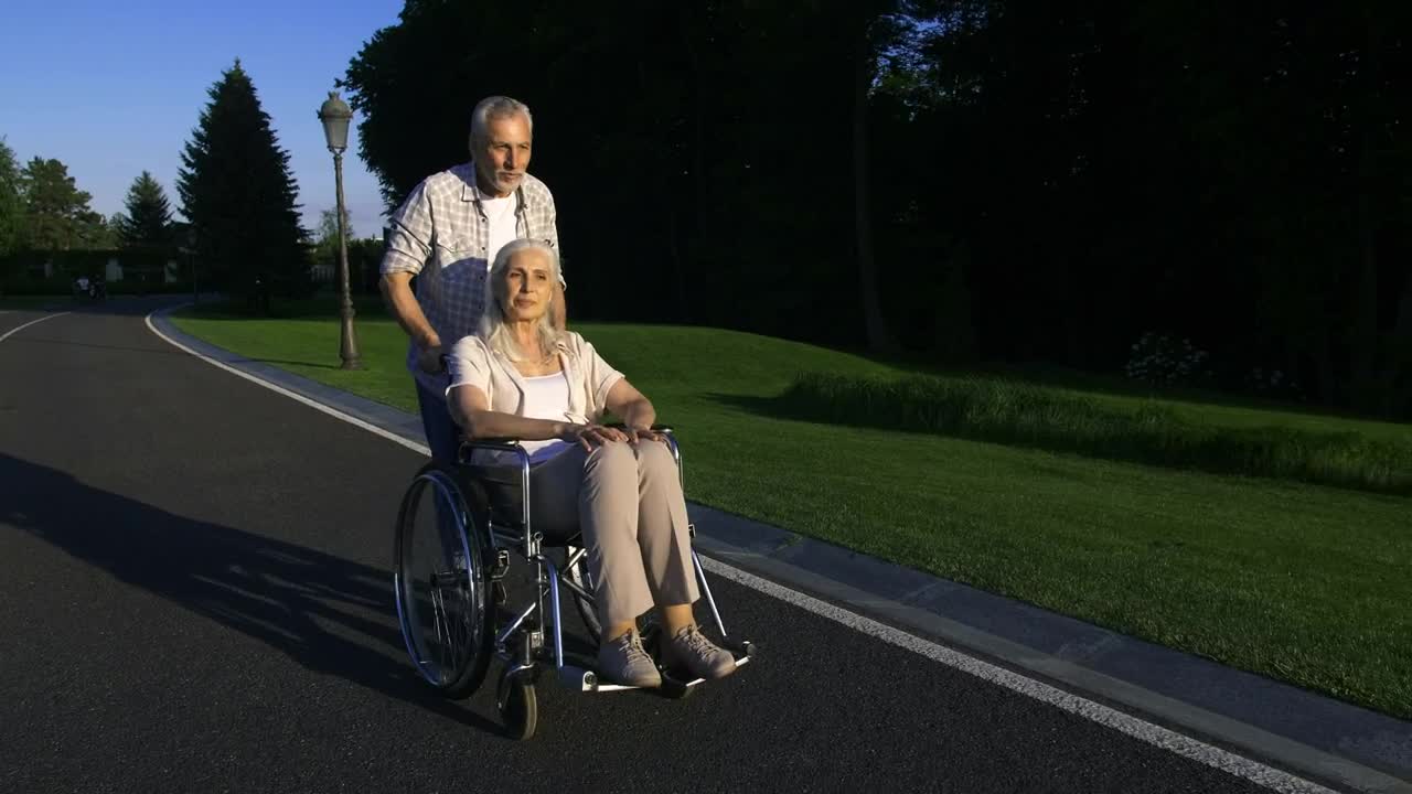 Stock Video Man Pushing His Wife In Her Wheelchai Animated Wallpaper