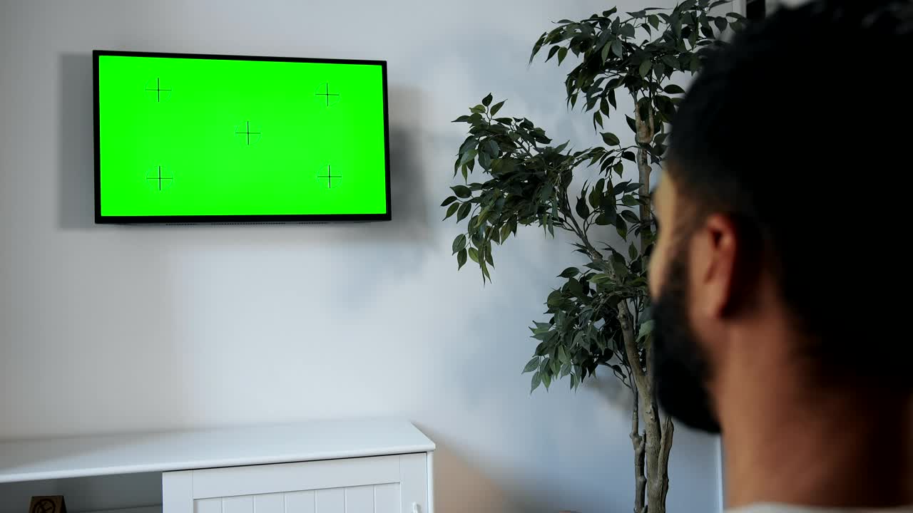Stock Video Man Points Remote At Green Screen Tv On Wal Animated Wallpaper
