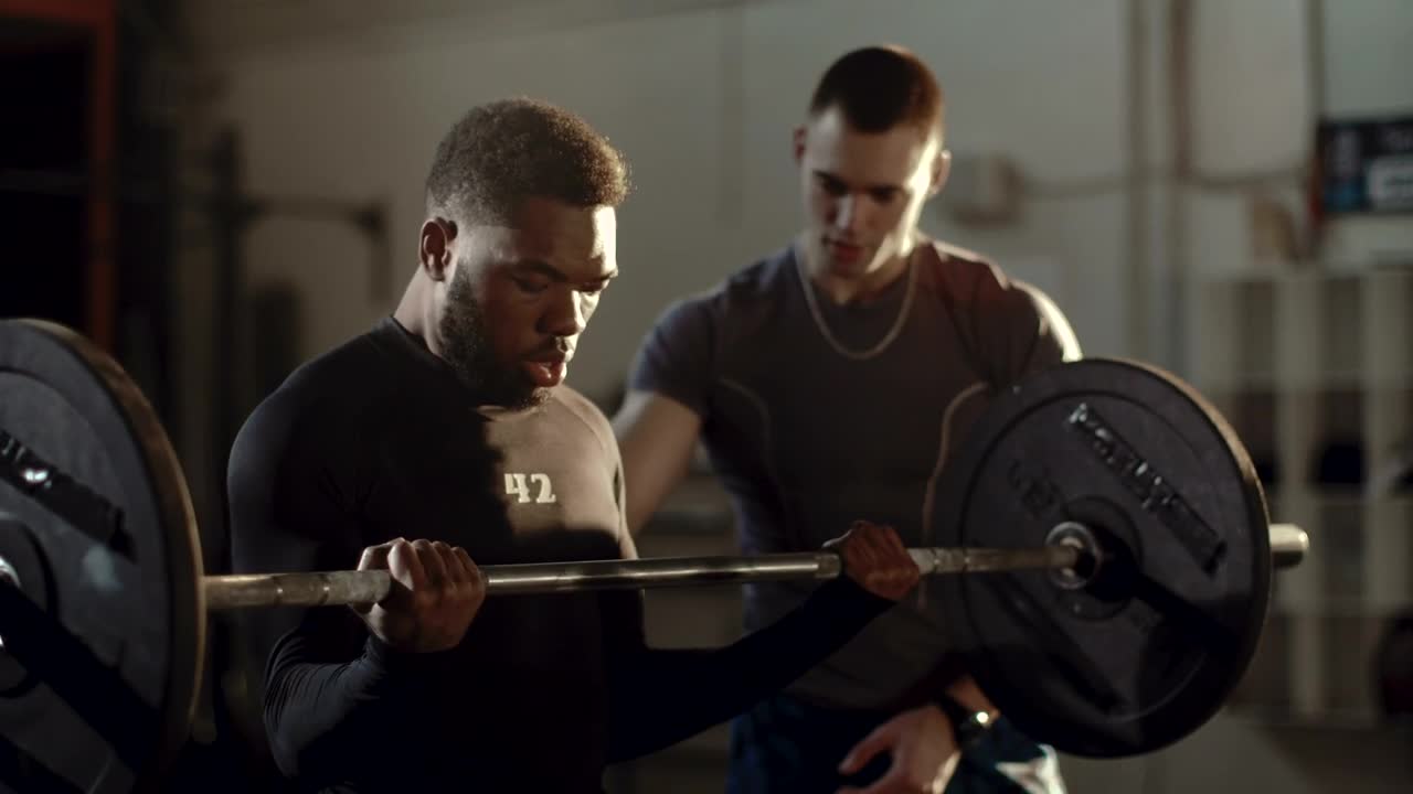 Stock Video Man Lifting Weights Supported By His Traine Animated Wallpaper