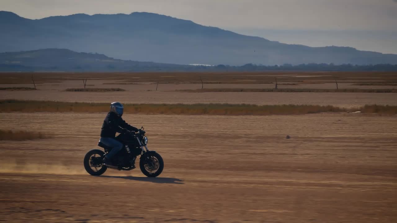 Stock Video Motorcyclist Crossing A Desert Surrounded By Mountains Live Wallpaper