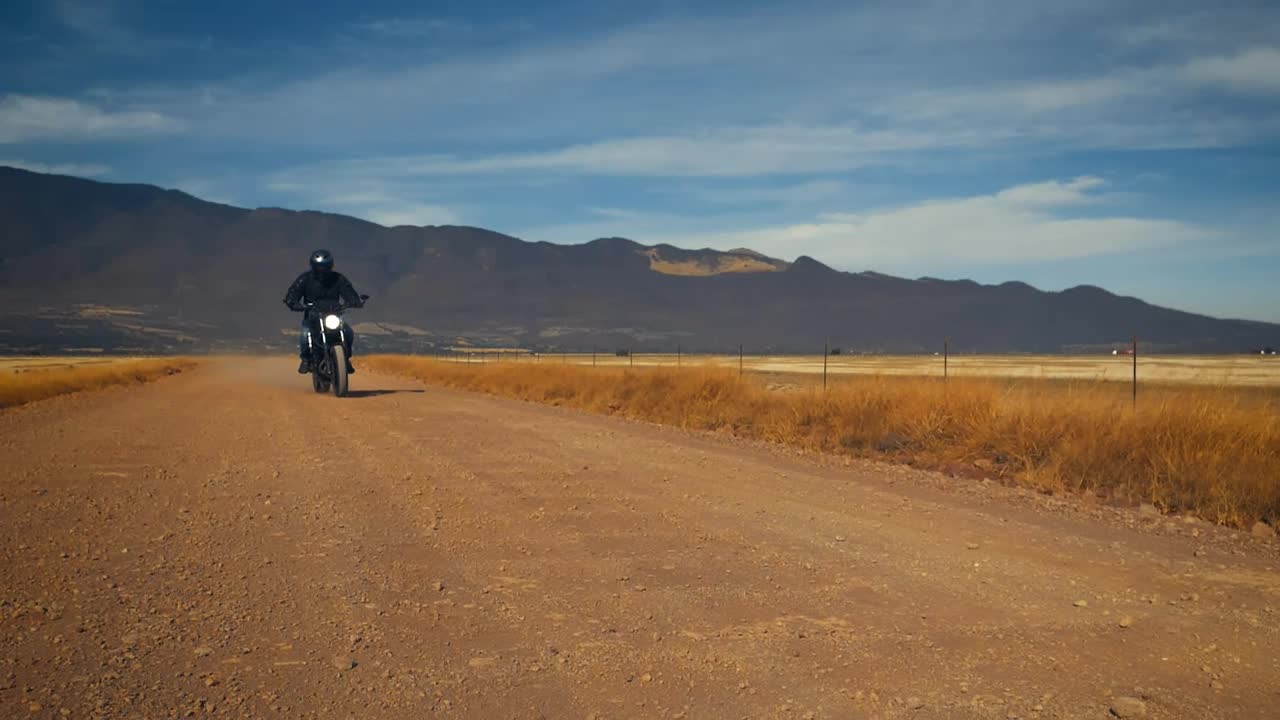 Stock Video Motorcyclist Crossing A Dirt Road In A Desert Live Wallpaper