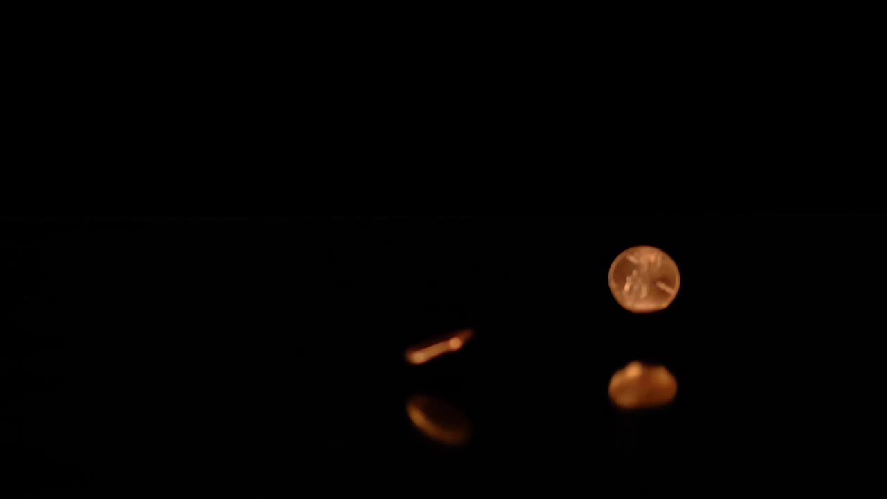 Stock Video Pennies Falling On A Reflective Surface With A Dark Background Live Wallpaper